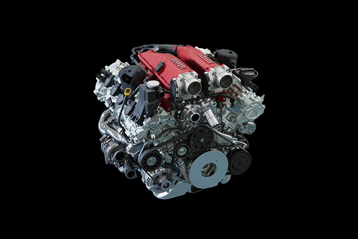 Powerful Ferrari engine with red valve covers and an intricate assembly of silver mechanical components.
