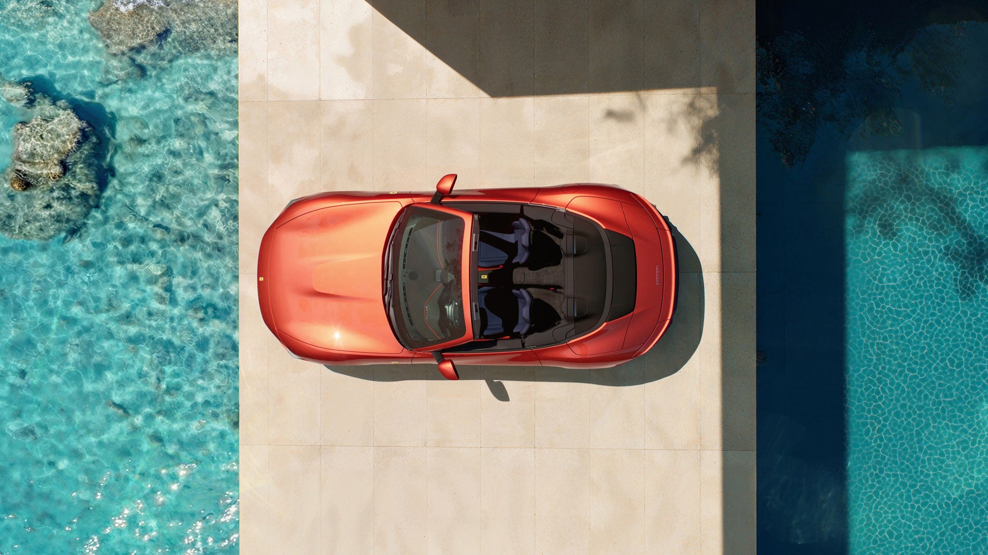 Rear view of a red Ferrari SP-8 on a racetrack with a black and white striped wall in the background.